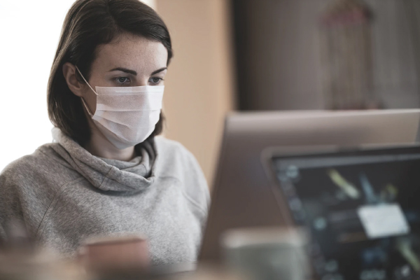 Female employee wearing a disposable facemask at her desk